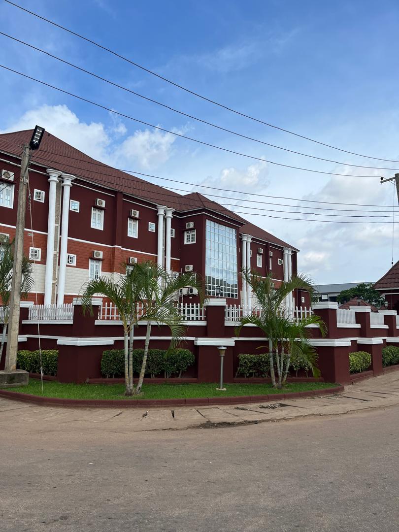 Mogadishu Metro Hotel building in daylight, with palm trees in front of the red and white facade