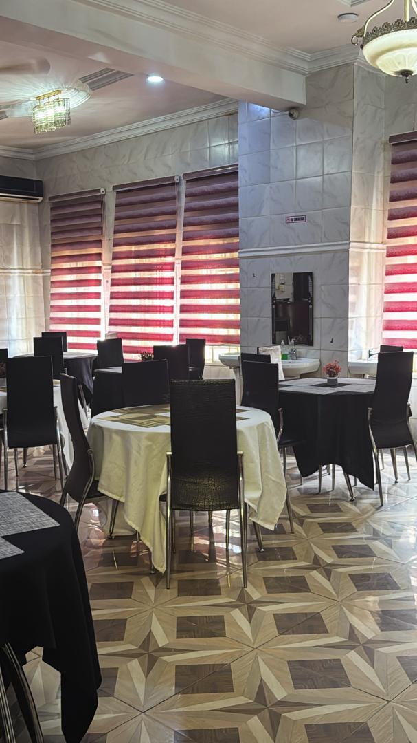 The hotel restaurant, with round tables, dark chairs and tiled floor