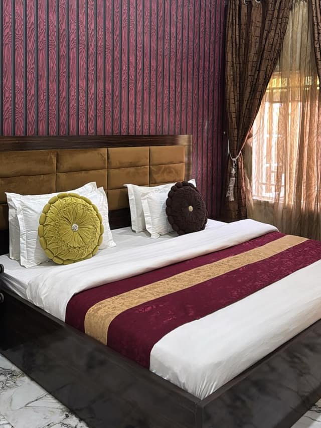 Business suite bed with burgundy and gold runner and striped feature wall