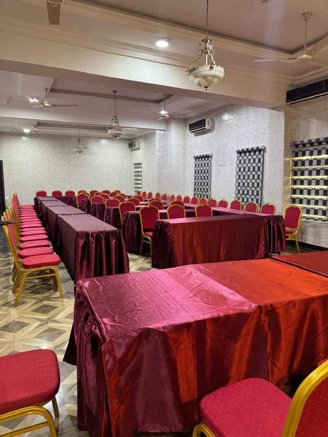 Conference hall set with maroon-draped tables and red and gold chairs