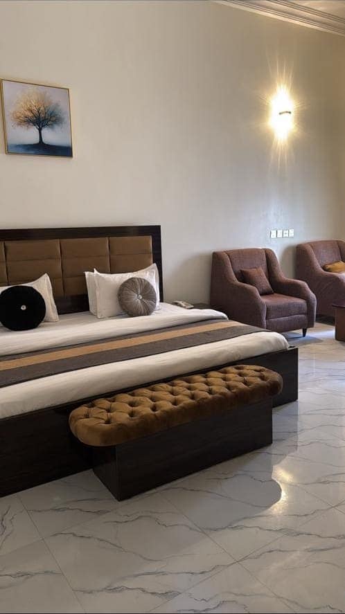 Executive room bed with tufted bench and framed tree painting