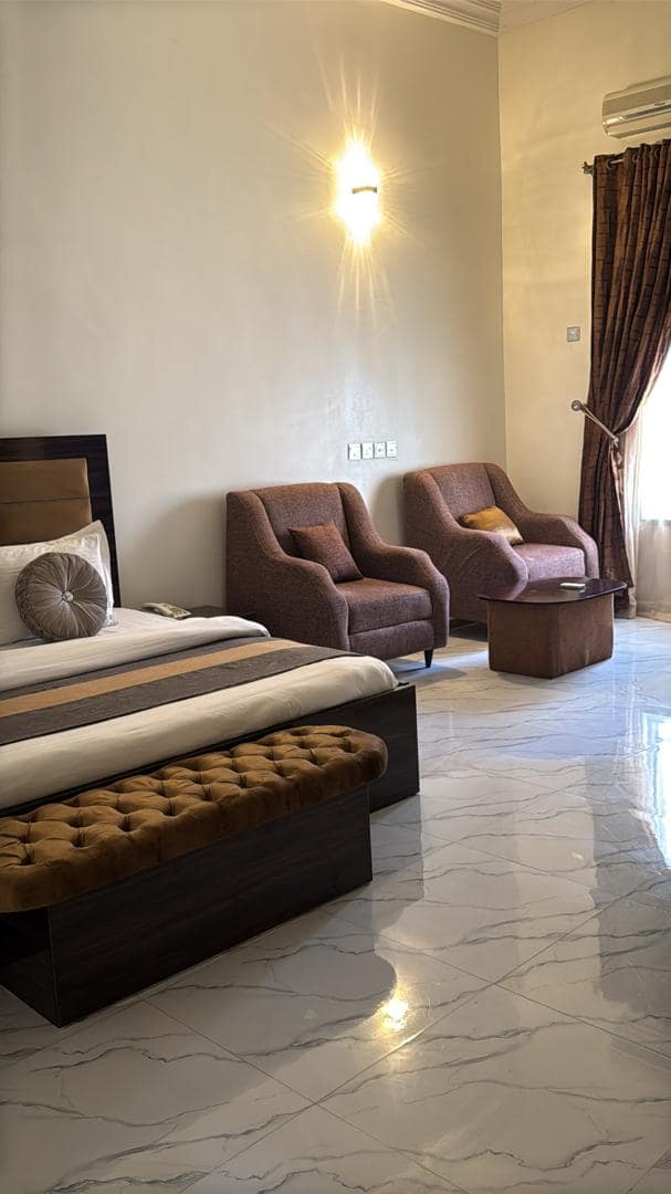 Executive room with armchairs and a wall light beside the bed