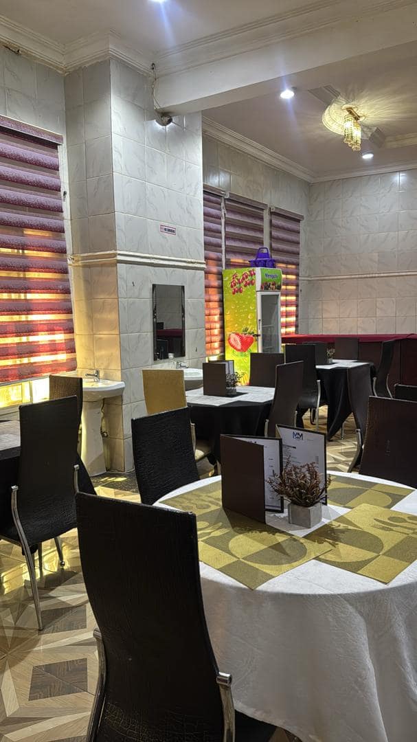 Restaurant tables set with menus and flowers, with the drinks fridge behind