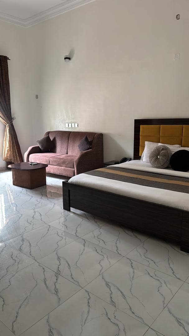 Superior room with bed, sofa and coffee table on a marble-style floor